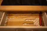 Open RV rental kitchen drawer neatly holds knives with sheaths and wooden cooking spatulas on a patterned liner.