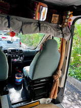 Discover this RV rental's front interior: comfy driver's seat, dashboard, and overhead storage with vibrant, colorful decor. Truck seen outside.