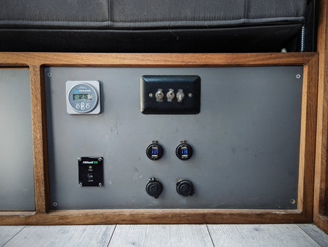 RV rental power panel: Victron battery monitor (12.16V), USB chargers, 12V outlets & switches.