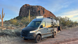 Grey Mercedes-Benz Sprinter RV rental parked in a desert landscape with saguaro cacti and a rocky mountain.