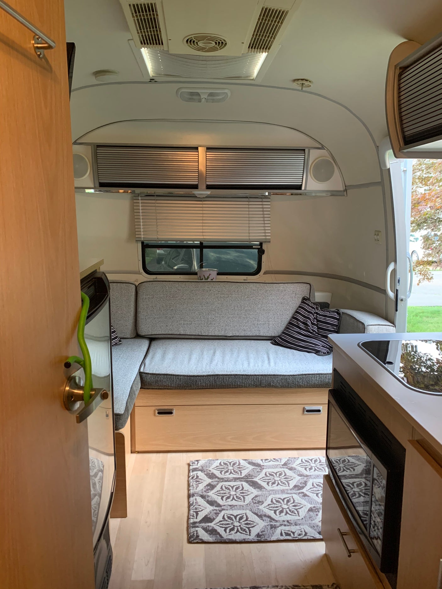Compact RV rental interior featuring a cozy living area with grey cushions, kitchenette, and smart storage for comfortable travel.