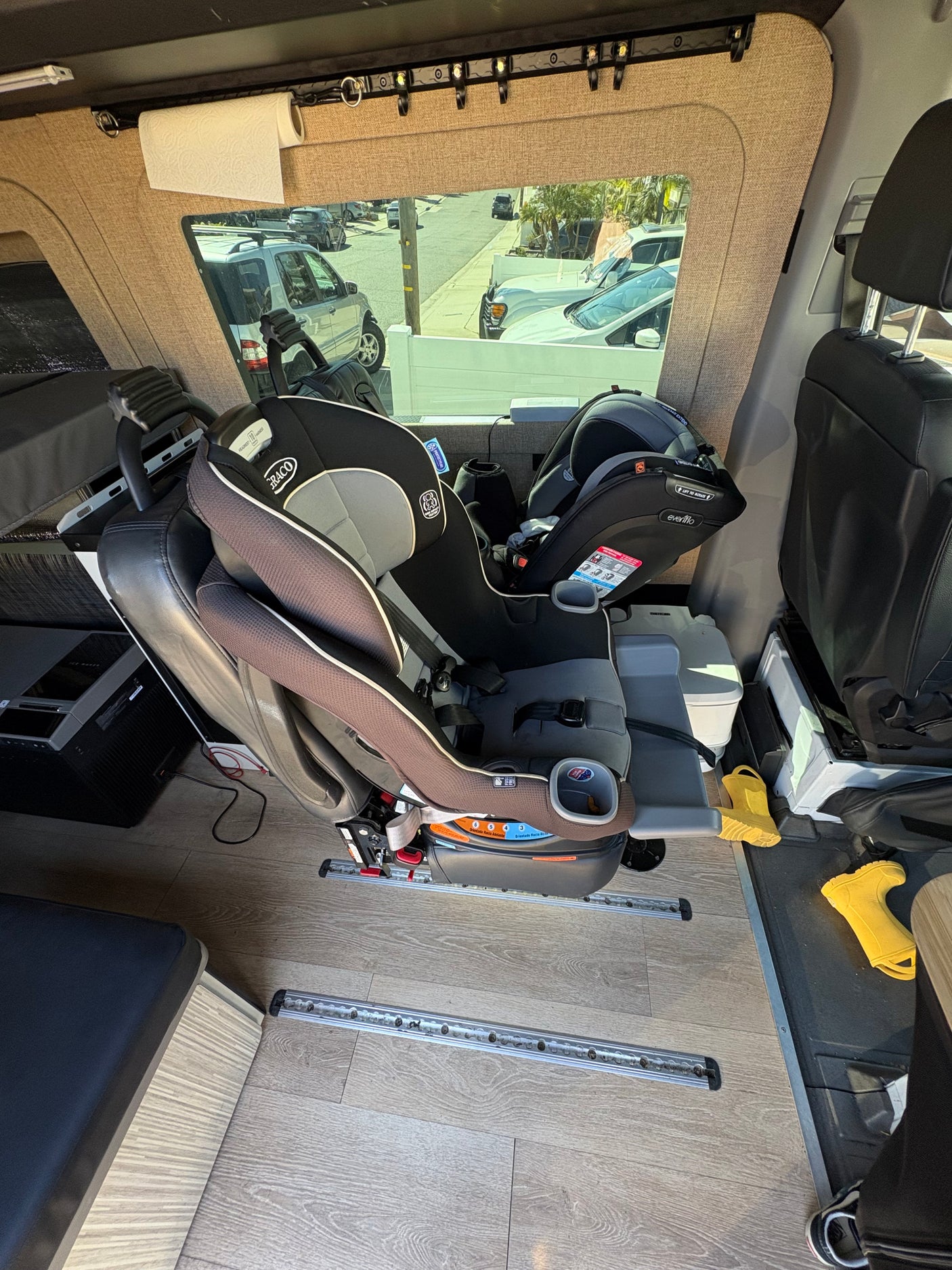 Family-friendly rv rental interior featuring Graco & Evenflo car seats, a paper towel roll, and floor track system.