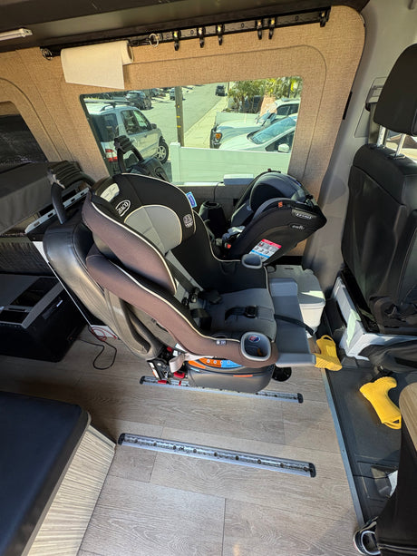 Family-friendly rv rental interior featuring Graco & Evenflo car seats, a paper towel roll, and floor track system.