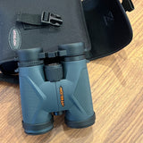 Athlon binoculars in their case on a wooden surface, essential gear for any RV rental adventure.