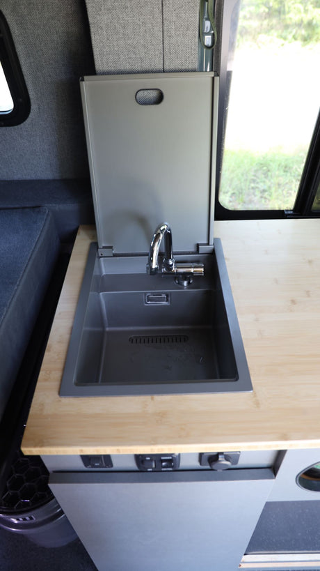 This RV rental showcases a clever, compact kitchen: a gray sink with a lift-up cover, chrome faucet, and bamboo counter.