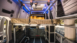 RV rental: Modular camper van interior with a raised bed, AC, controls, and smart storage.