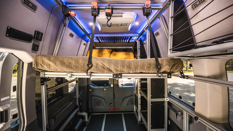 RV rental: Modular camper van interior with a raised bed, AC, controls, and smart storage.