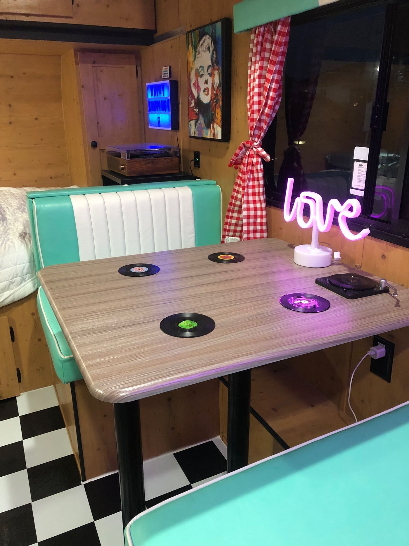 Experience a retro vibe in this RV rental featuring a 50s diner-style booth, record table, & neon 'love' sign. — photo 4