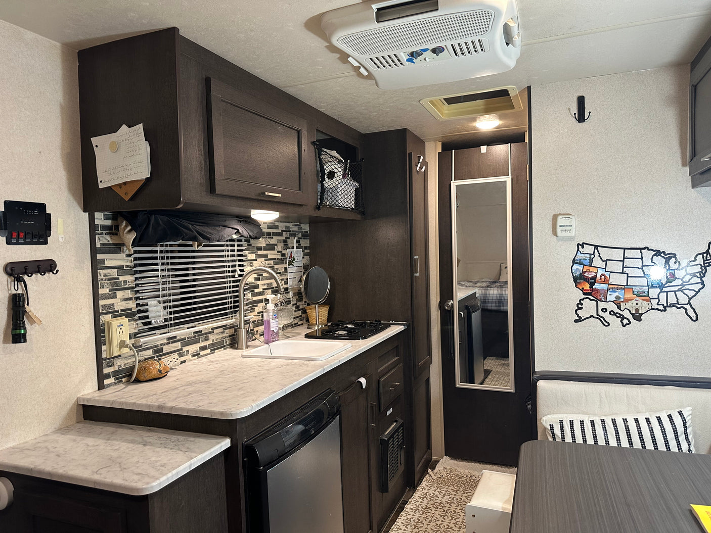 Compact RV rental kitchenette & dining area featuring Dometic appliances, Suburban controls, and cozy decor.