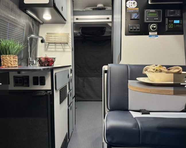  facing the ocean.|A stylish beige and gray Sprinter RV rental parked in a tranquil forest campground — photo 6