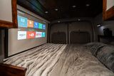 Cozy RV rental interior with a large projector screen displaying Netflix, YouTube, and Amazon over a plush bed.