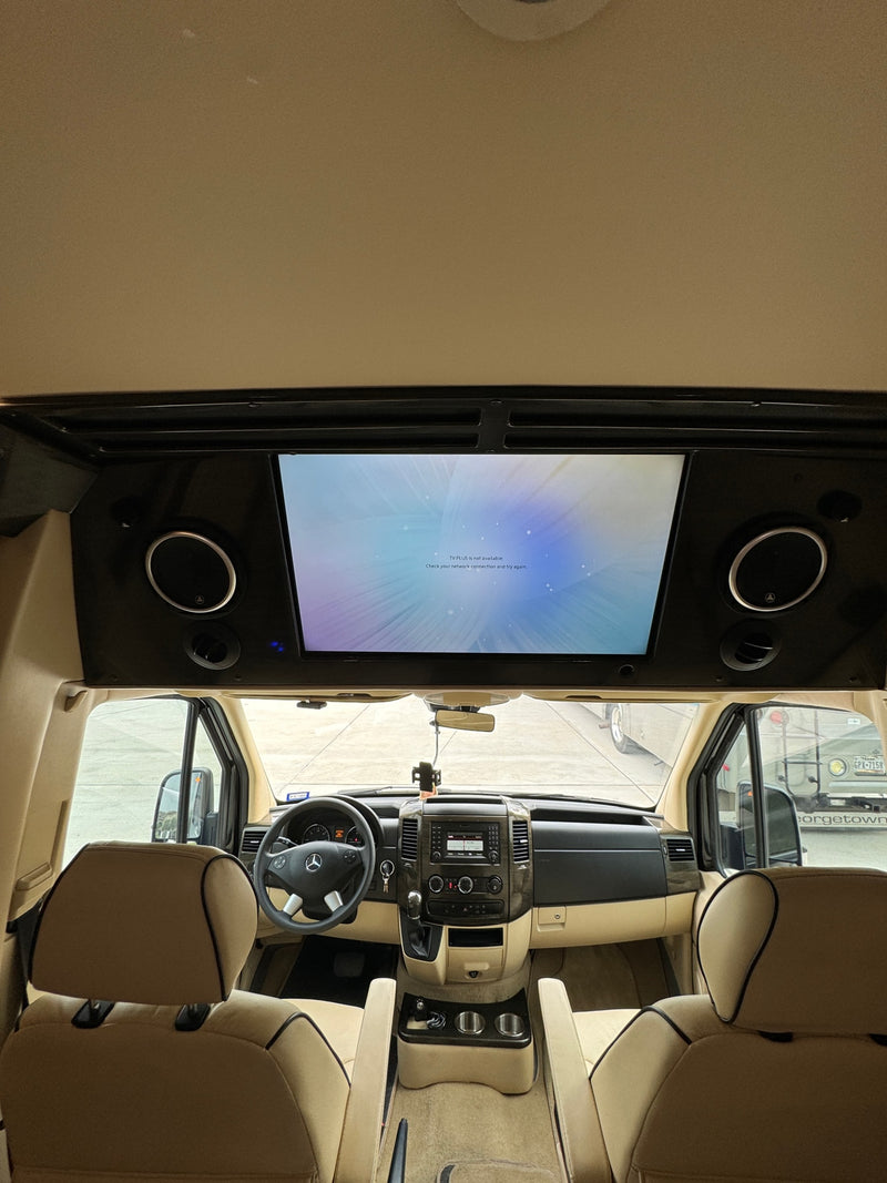 Interior view of an RV rental, highlighting the Mercedes-Benz dashboard, front seats, and an overhead TV displaying a network error message. — photo 11