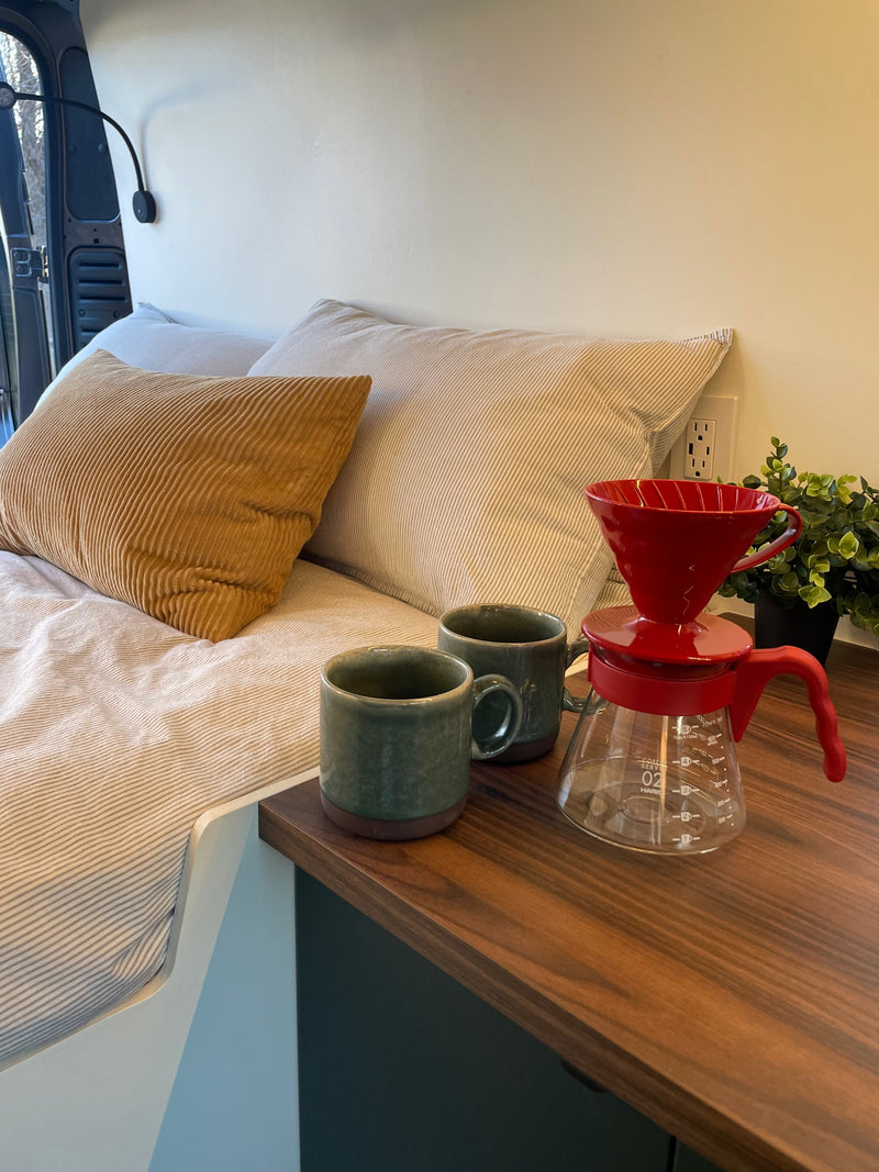 Cozy morning coffee setup in an rv rental, featuring a bed with pillows, mugs, and a pour-over coffee maker. — photo 15