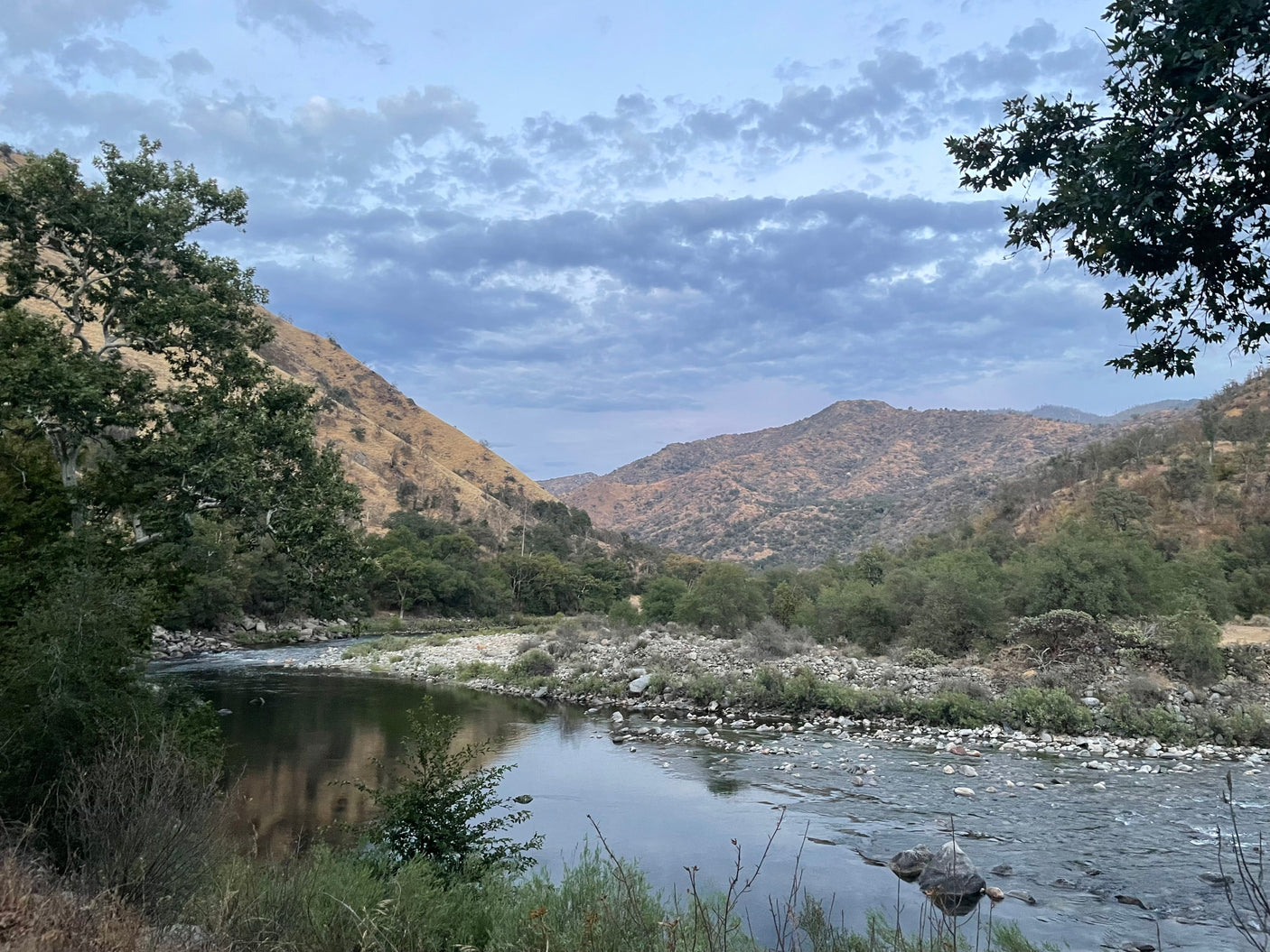 Scenic river flowing through a mountain valley under cloudy skies. Perfect for an RV rental adventure to explore nature's beauty.