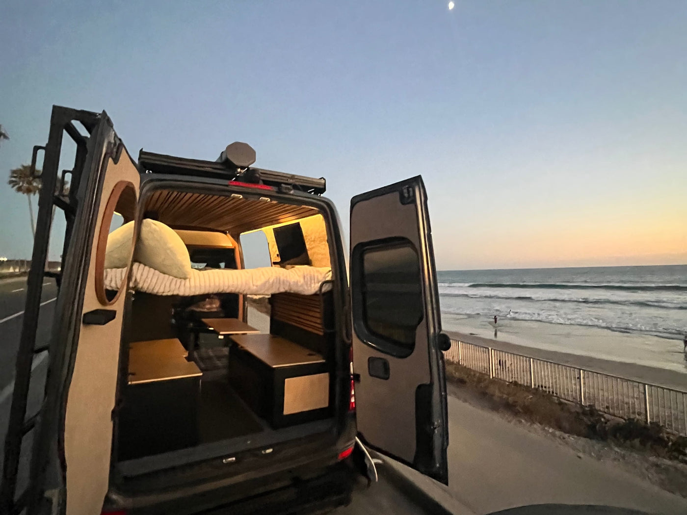 Open doors of an rv rental van reveal a cozy interior with a bed — photo 1