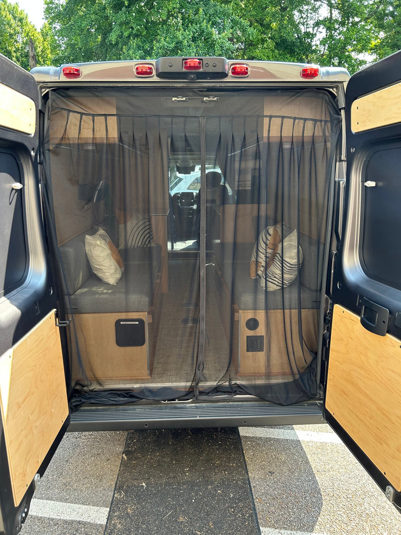 The RV rental's rear is open, revealing a bug screen, interior benches, and a clear view towards the front cabin. — photo 9