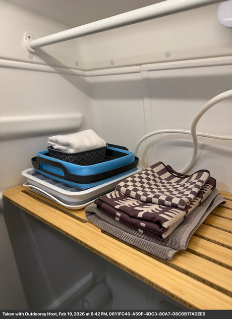 RV rental offers convenient storage: collapsible basins & fresh towels neatly organized on a slatted shelf for compact living.