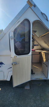 This A-frame RV rental features an open door, revealing a compact interior with a kitchen, perfect for your next adventure.