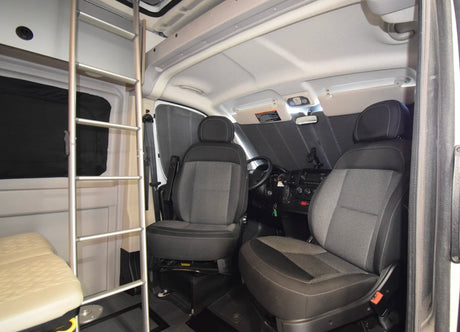 RV rental: Interior of a camper van's front cabin, showing driver/passenger seats, dashboard, and a ladder to an upper bunk.