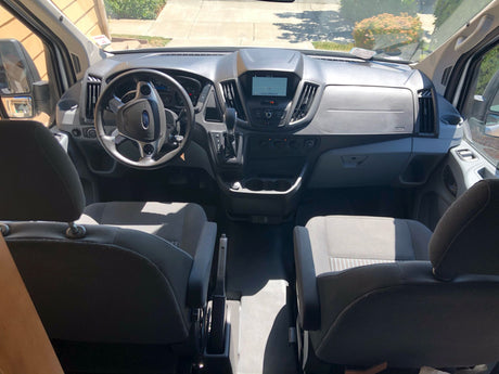 RV rental van interior showing the driver's area, dashboard with navigation screen, and front seats. Ideal for road trips.