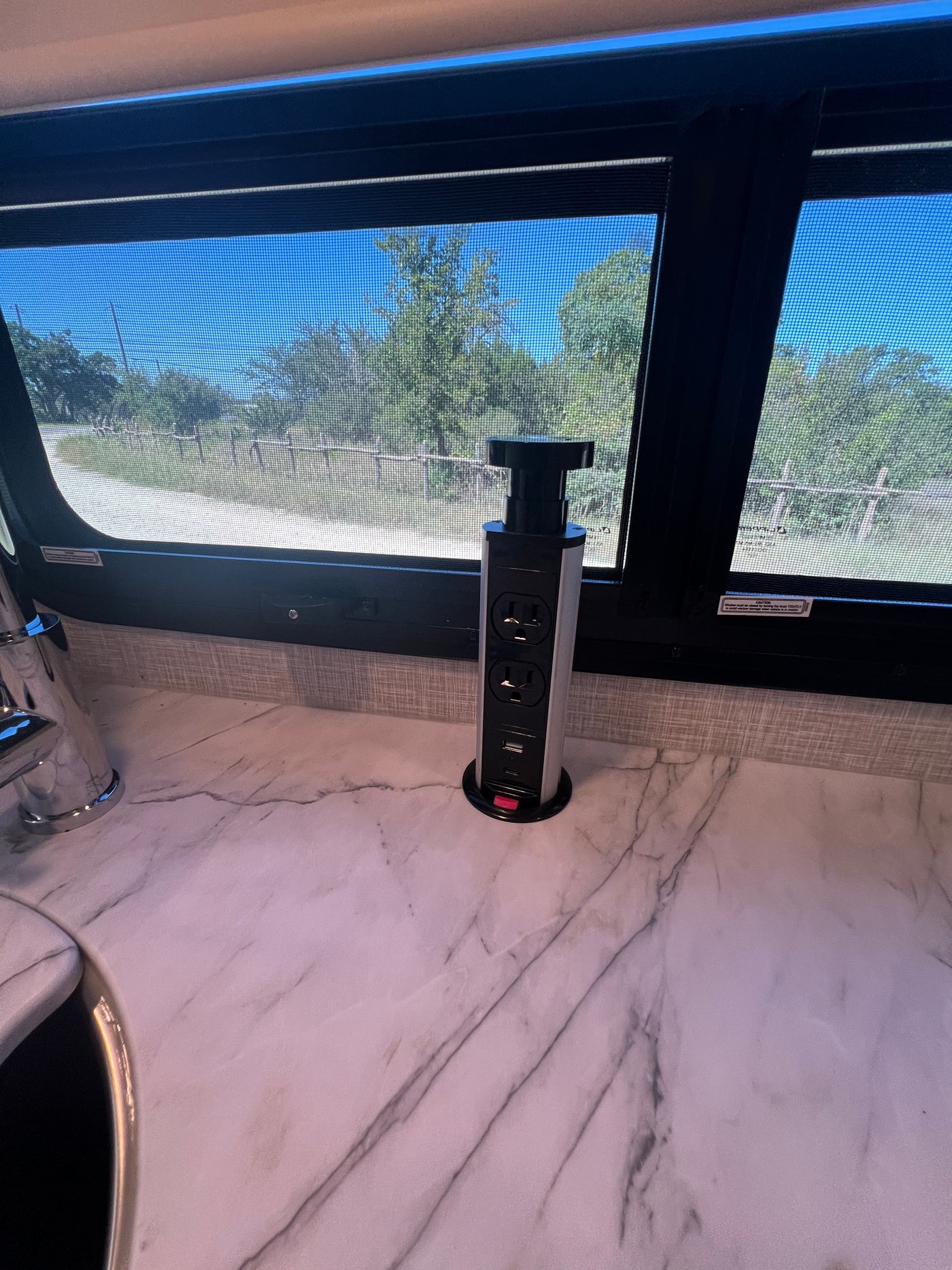 Pop-up power tower with AC & USB in an RV rental kitchen. White marble-look counter and window view. — photo 19
