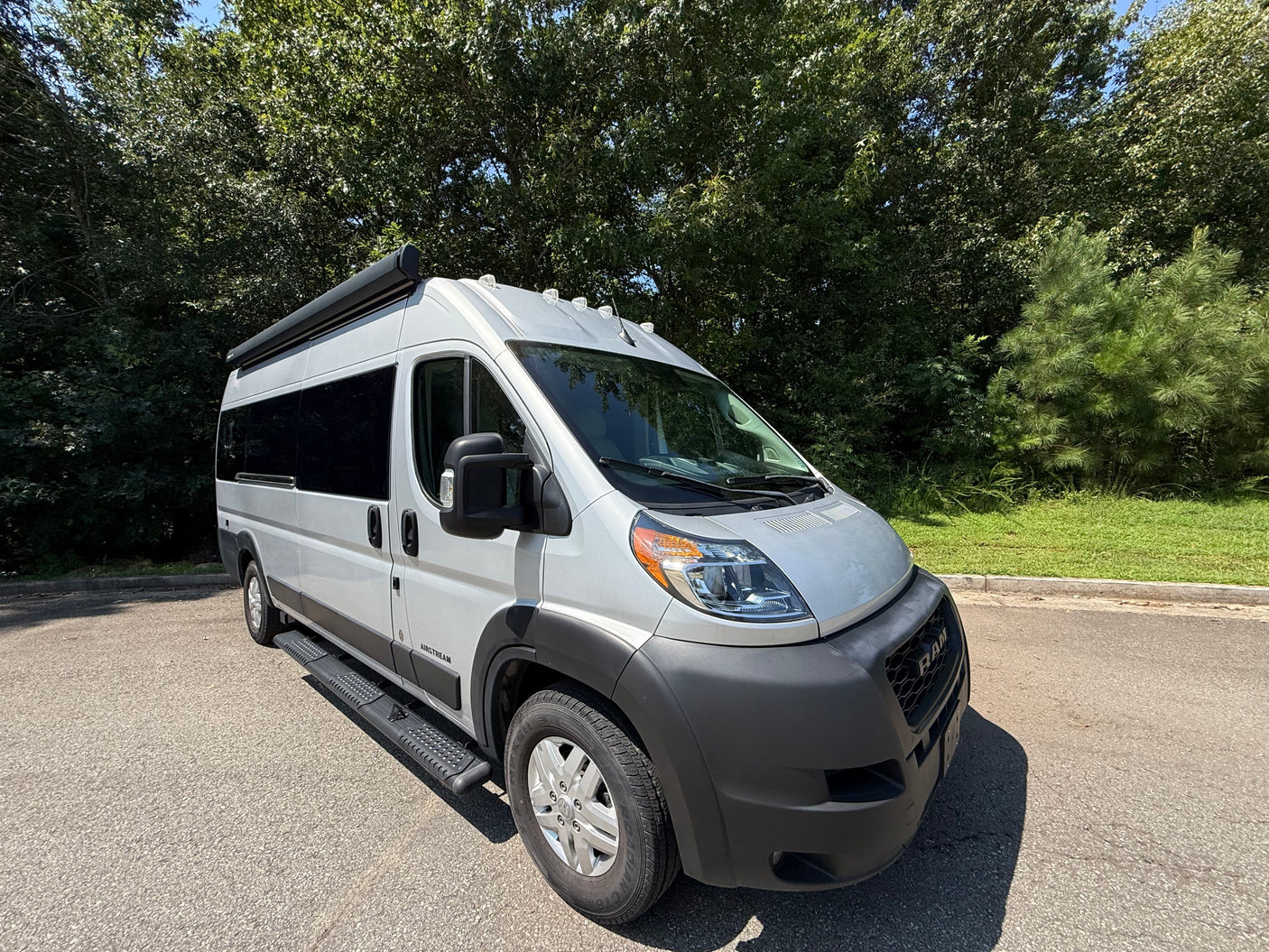 Bright day showcasing a sleek gray Airstream camper van, perfect for your next rv rental adventure, parked on asphalt.