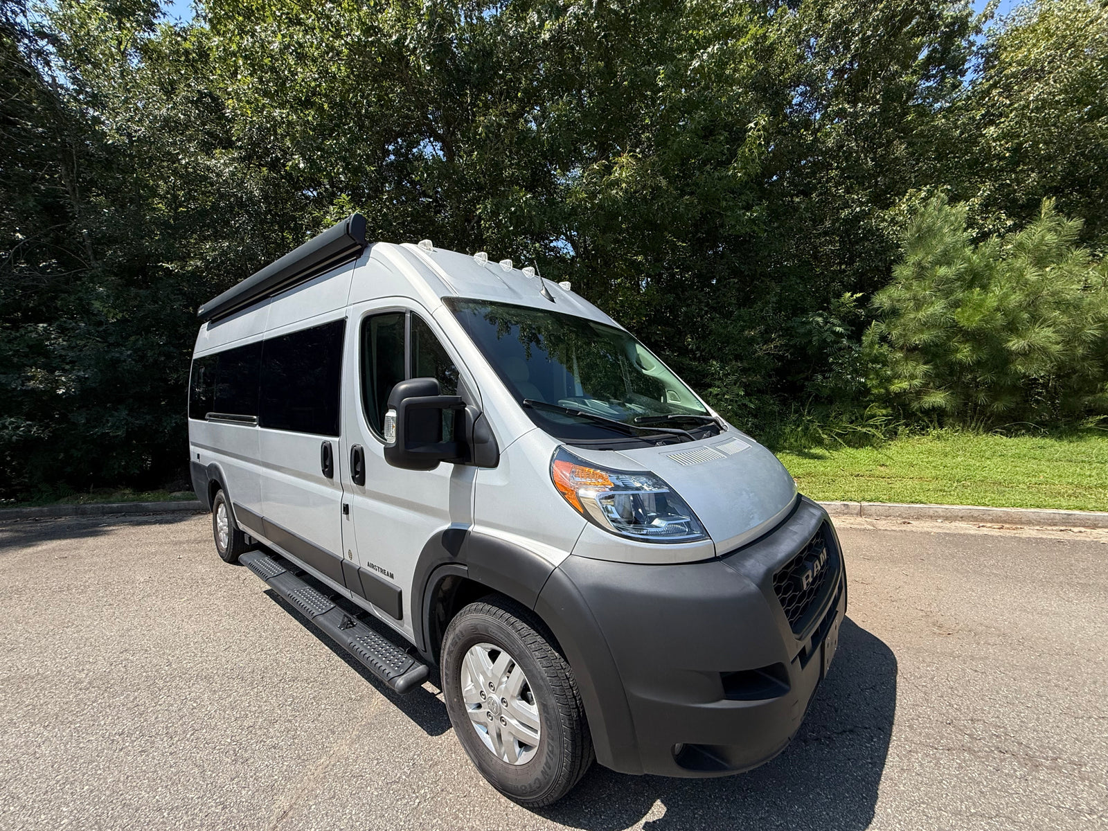 Bright day showcasing a sleek gray Airstream camper van, perfect for your next rv rental adventure, parked on asphalt.