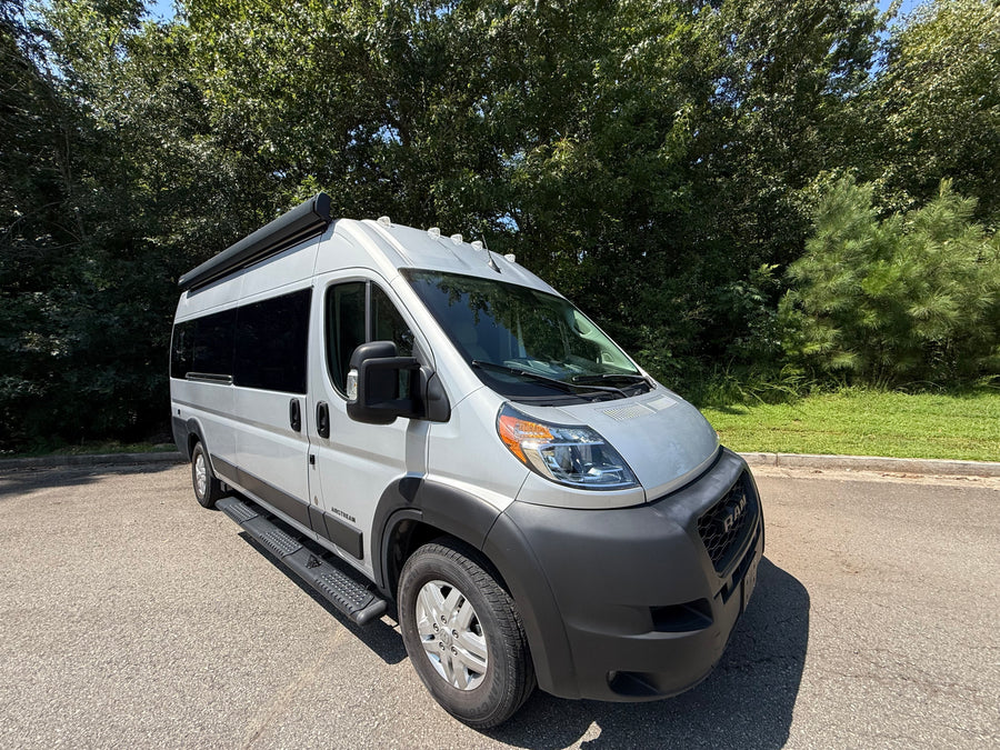 Bright day showcasing a sleek gray Airstream camper van, perfect for your next rv rental adventure, parked on asphalt.