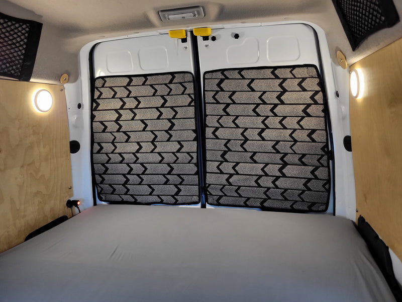  with a rainy view outside.|This RV rental features a cozy sleeping area: a grey mattress on a wooden slat bed — photo 12