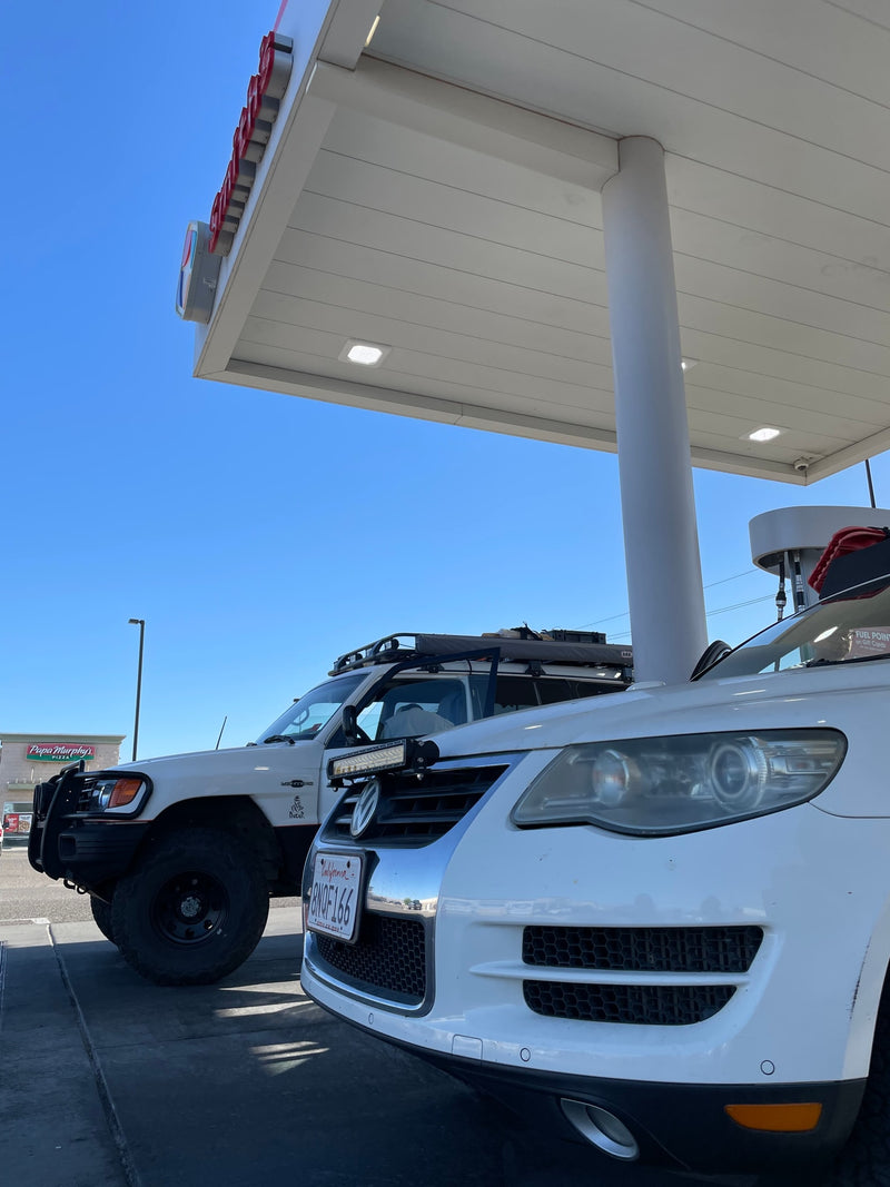 Two white adventure vehicles, an off-road SUV & VW Touareg, refueling at a station, perfect for an RV rental trip. — photo 9