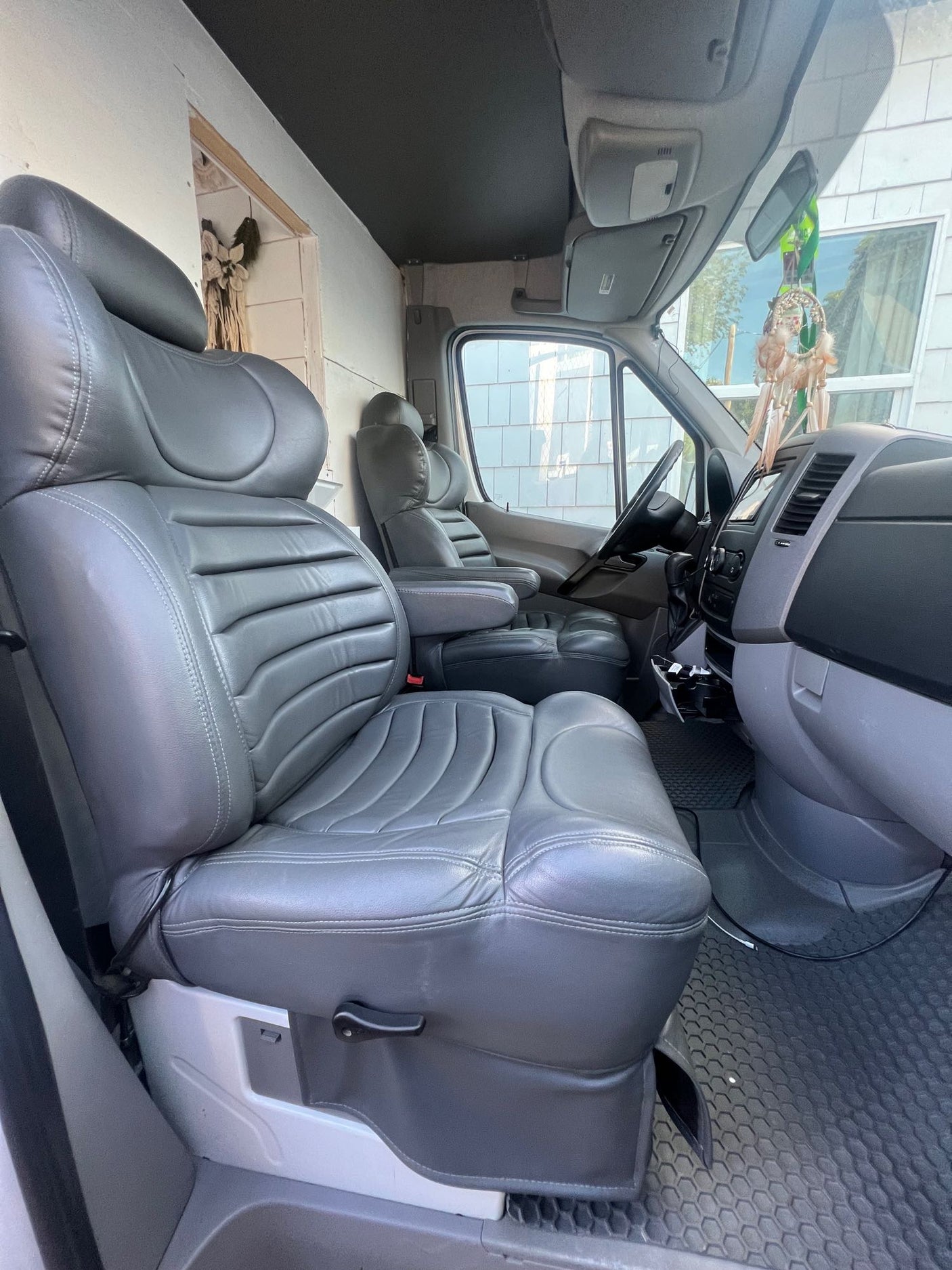 Spacious RV rental camper van interior. Features custom grey seats, driver's cockpit, and partition to the rear living area.