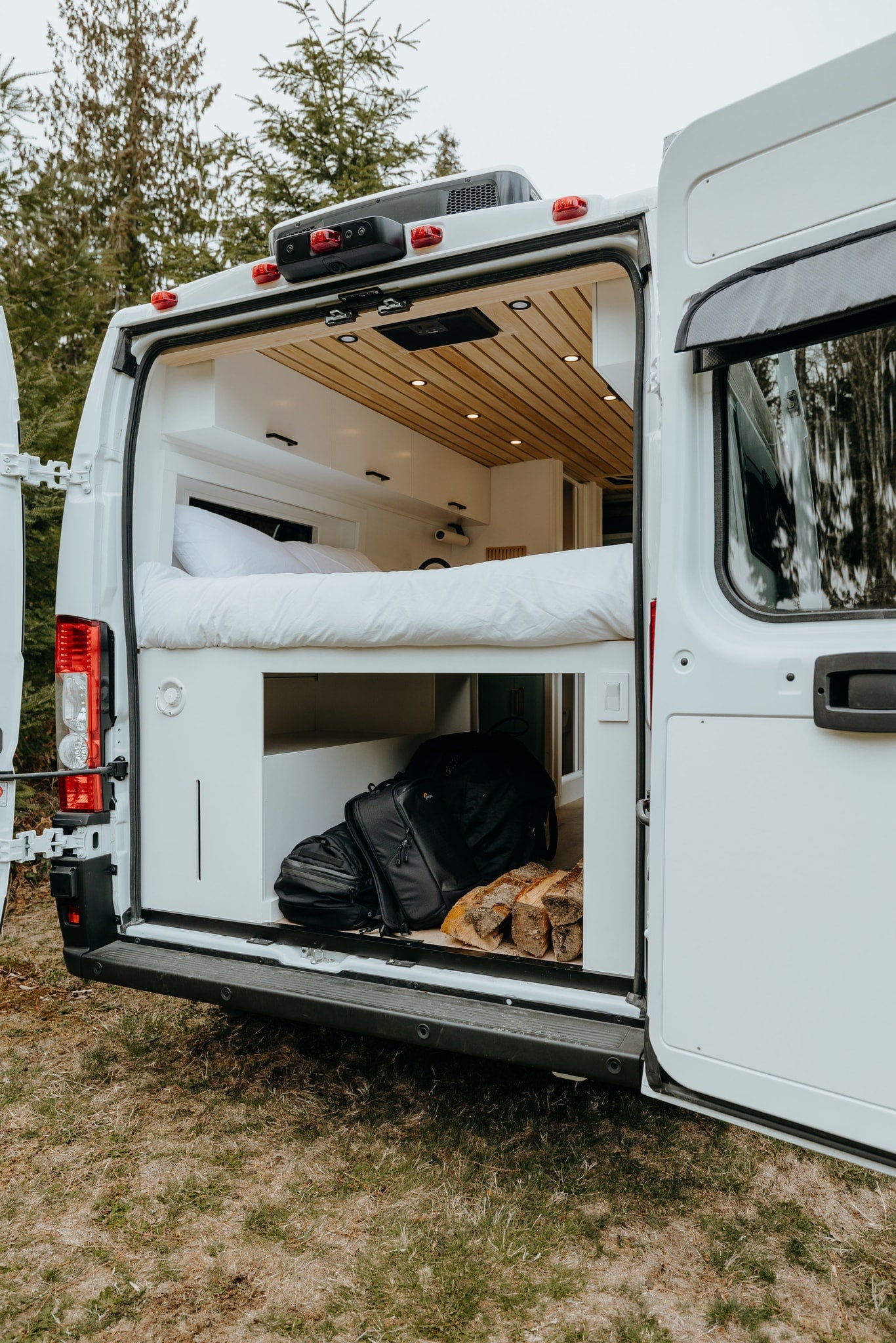 Spacious RV rental interior featuring a cozy bed, ample storage for travel gear & firewood. Perfect for adventure! — photo 3