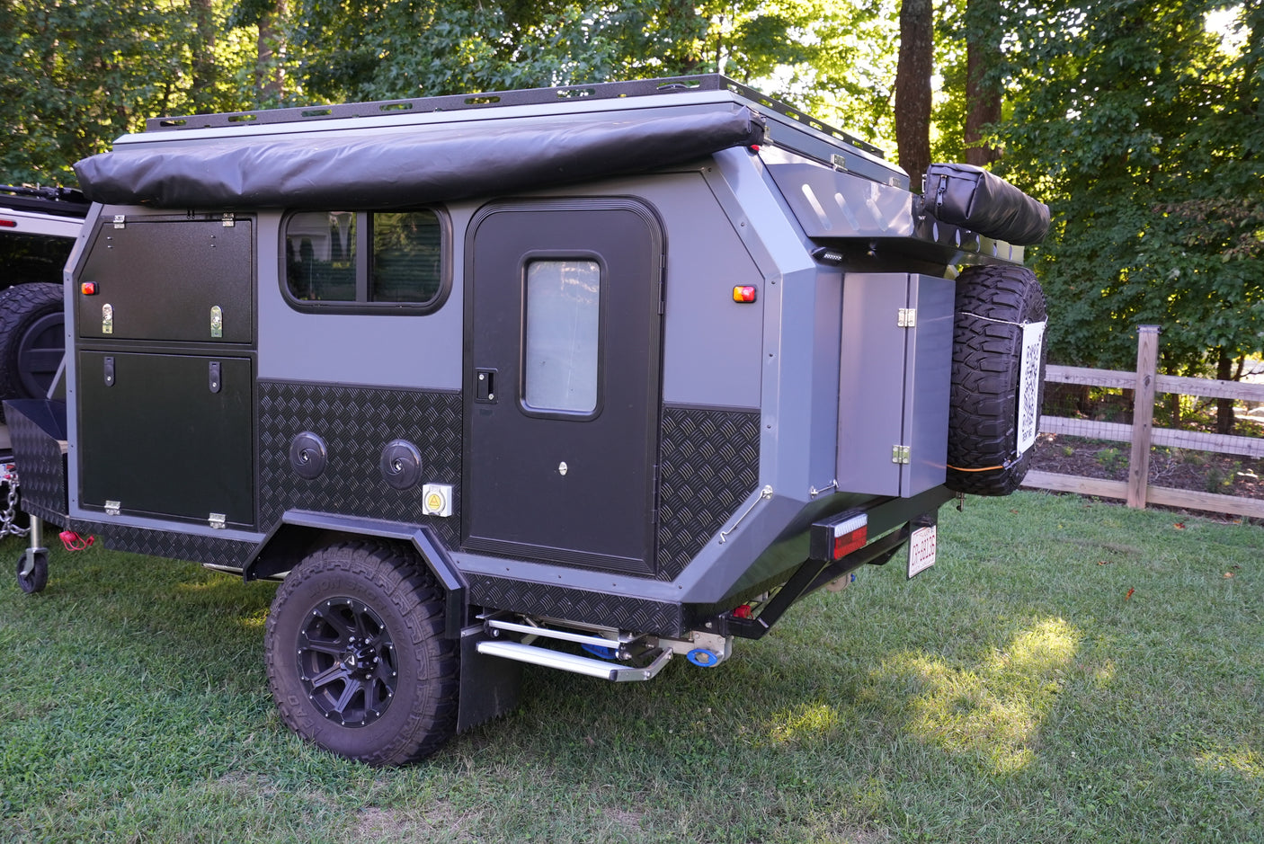 A robust grey off-road camper trailer, featuring an awning and storage, ideal for adventure rv rental and outdoor exploration.