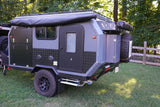 A robust grey off-road camper trailer, featuring an awning and storage, ideal for adventure rv rental and outdoor exploration.