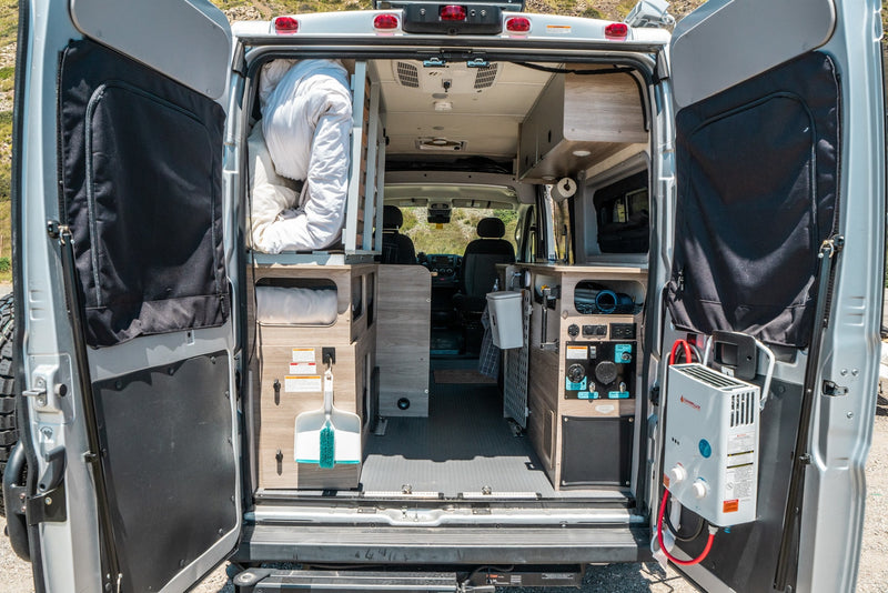 RV rental interior: A detailed rear view shows a functional camper van with bed, kitchen, storage, and a portable water heater. — photo 11