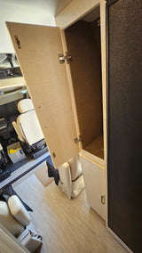 RV rental interior features: an open light-colored cabinet with a dark felt lining, adjacent to a dark appliance, near cabin seating.