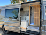 View inside a grey camper van, an ideal RV rental. It features a modern kitchen, shower, and slatted wood accents.