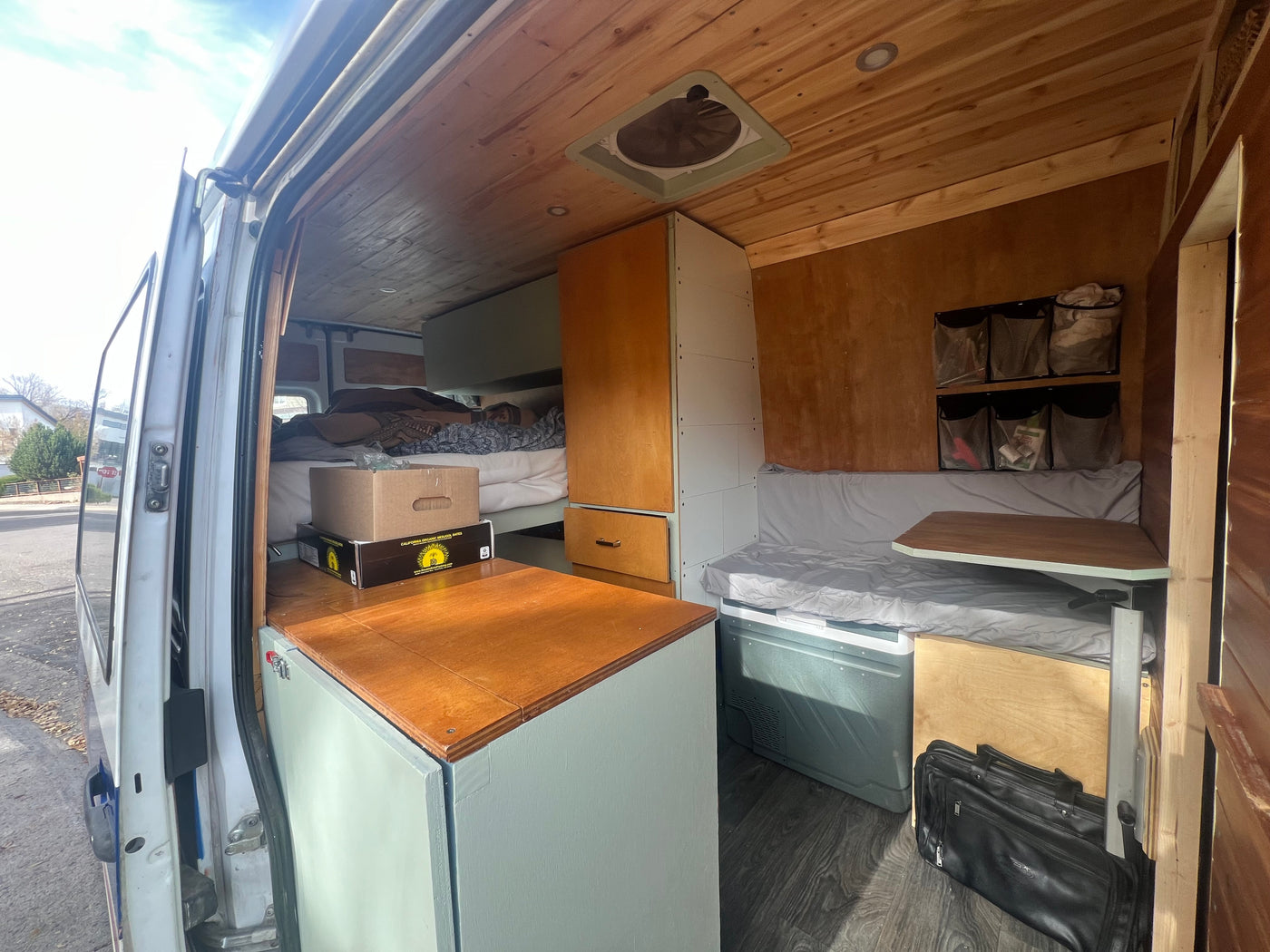 Inside a custom RV rental: A well-designed camper van interior with a bed, wood accents, and seating for adventures. — photo 2