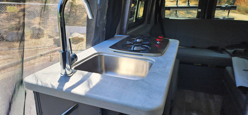 Compact kitchen in an RV rental, featuring a chrome faucet, stainless steel sink, and two-burner stove by a screened window. — photo 4