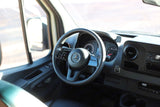 RV rental interior: Mercedes-Benz steering wheel, dashboard, and door panel with controls from the driver's perspective.