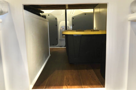 RV rental storage: A black bin with a yellow lid and a silver appliance inside a compact storage bay.