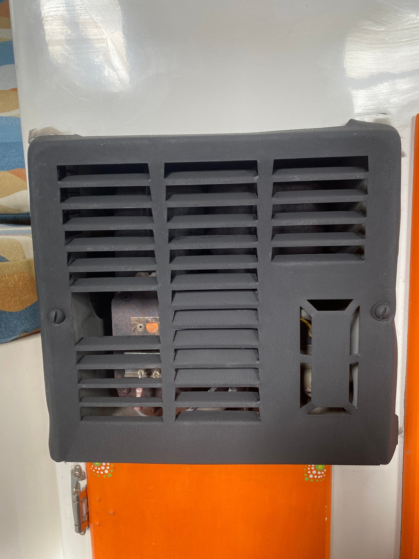 Close-up of an RV rental's black furnace heater vent cover, revealing interior components for heating.
