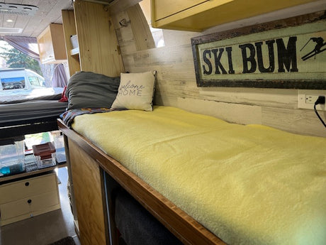 Inside this unique RV rental, discover cozy bunk beds, warm wooden paneling, and a "SKI BUM" sign.