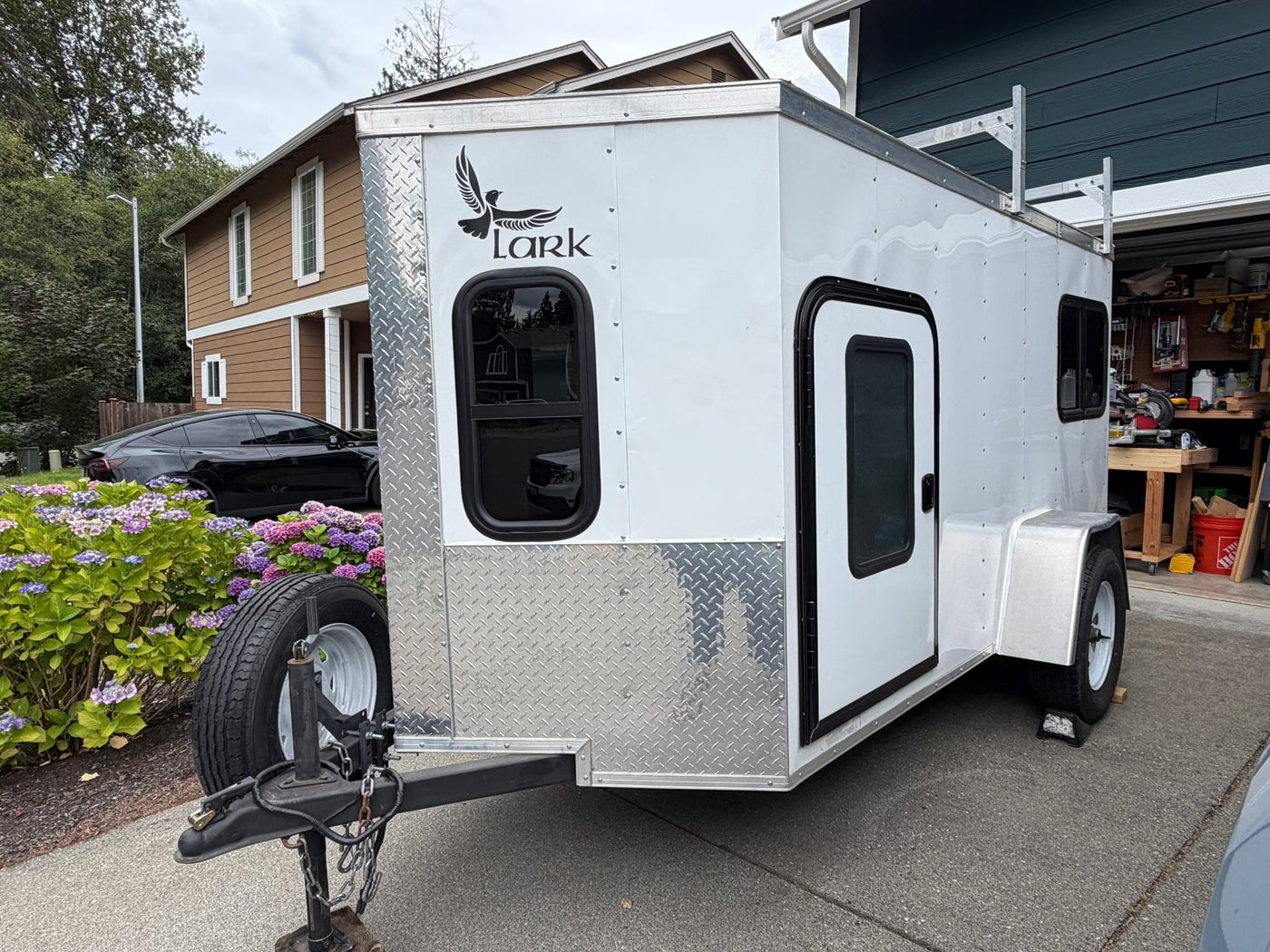 A white custom camper trailer with a "Lark" bird logo — photo 1