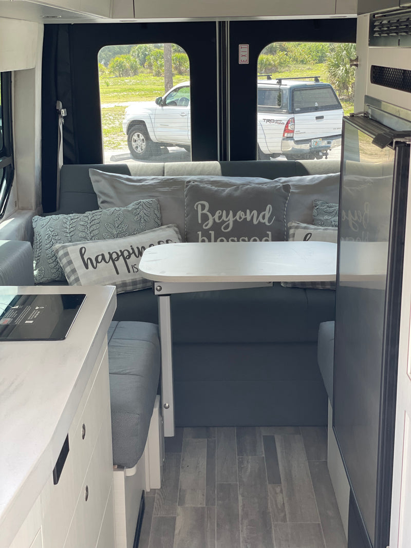 RV rental: Modern interior with a cozy gray bed and decorative pillows, a sleek white table, and microwave unit. — photo 5