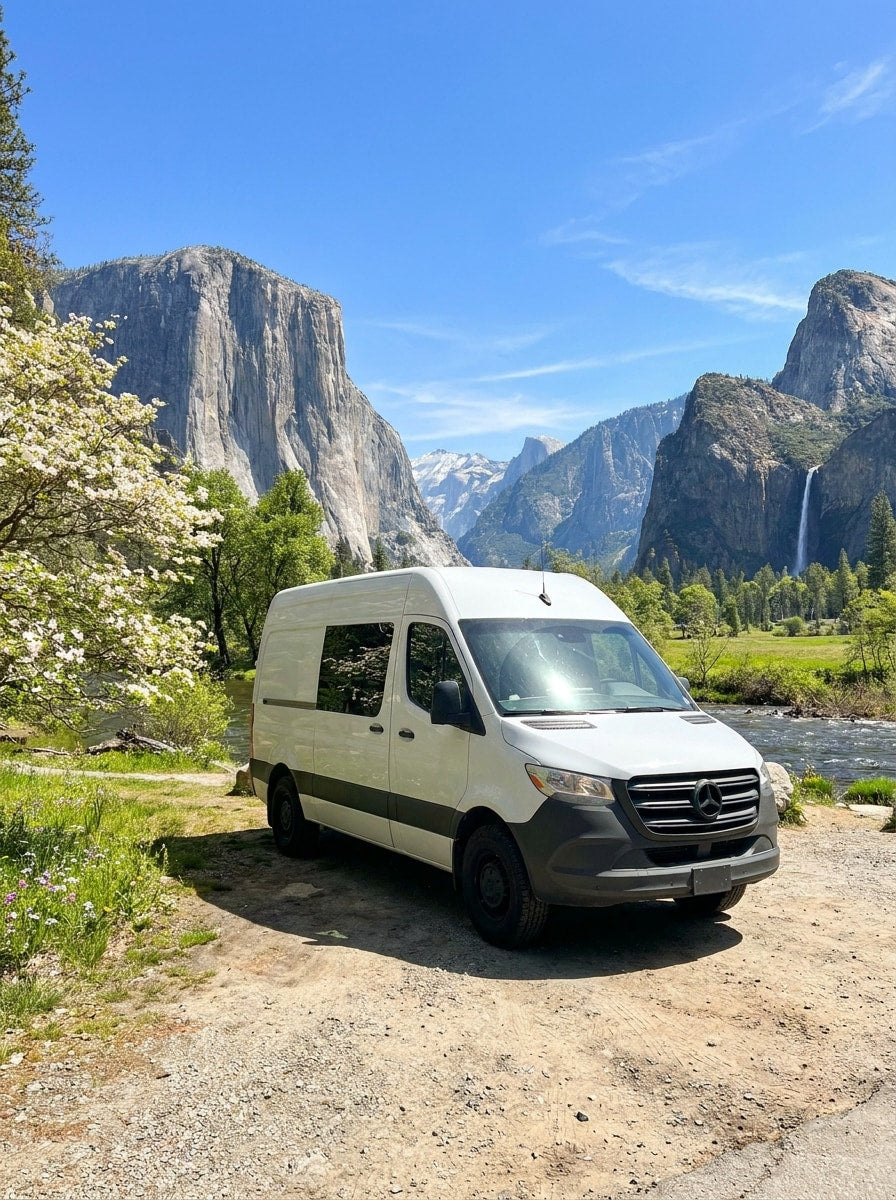  and a tranquil view of a field at dusk. Features a unique red embroidered cushion.|This RV rental offers a refreshing outdoor shower in a serene forest setting. The camper van's rear doors are open — photo 6