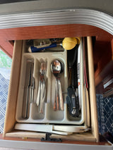 Inside an RV rental kitchen drawer: neatly organized cutlery, a knife, and various tools, ready for your road trip meals.