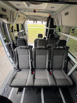 RV rental van interior: modular seating & track system for flexible travel. Open rear doors reveal scenic view.