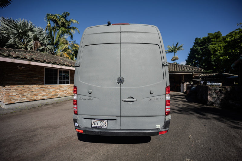 Rear view of a textured gray Mercedes Sprinter van, likely an RV rental, parked on an asphalt driveway in sunny Hawaii. — photo 14