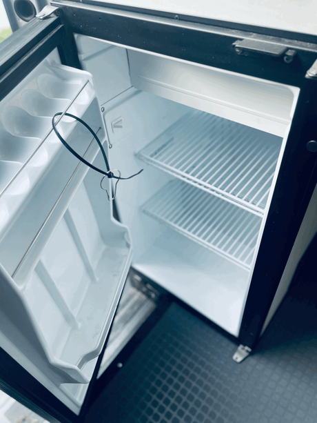 Clean, empty mini-fridge in an RV rental, ready for your adventure essentials.